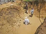 mit Eimern schoepfen die Maenner den Schlamm aus der Grube - Bauarbeiten beim Chathura-Kinderheim in Sri Lanka 