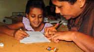 Vinitha zeigt Harshani im Chathura-Kinderheim wie man die singhalesischen Buchstaben schreibt